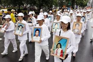 Последователи на Фалун Гонг в бяло траурно облекло носят фотографии на убити от комунистическия режим практикуващи в Китай. Тайван. 
